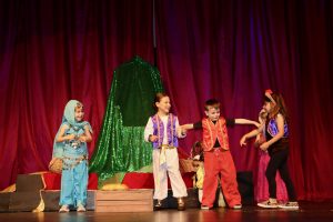 Young Kids On Stage actors perform in colorful costumes during an Aladdin-inspired children’s theater show.