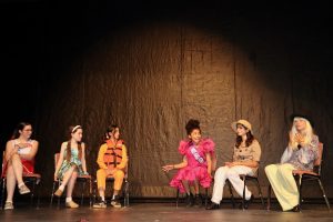 Kids On Stage actors seated on stage in costume during a Beetlejuice-inspired youth theater performance.